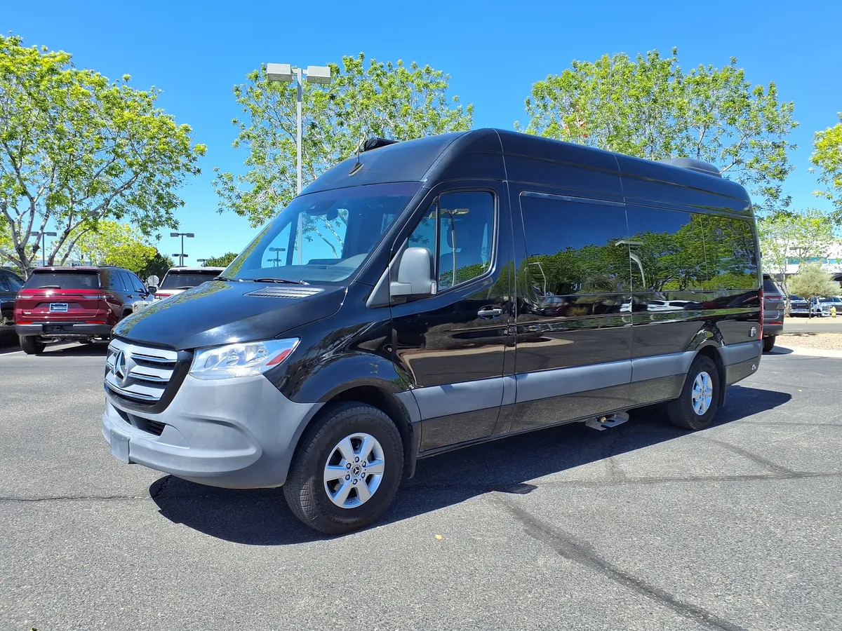A black high-roof Mercedes-Benz Sprinter passenger van in a parking lot