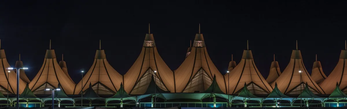 The peaked white roof of the Jeppesen Terminal at Denver International Airport, lit up before sunrise