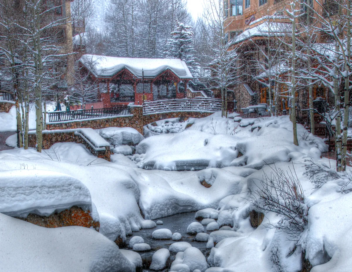 A footbridge over the creek in Beaver Creek village during snowfall